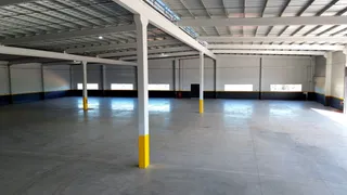 Espaço interno de um galpão industrial com estrutura de vigas e colunas.