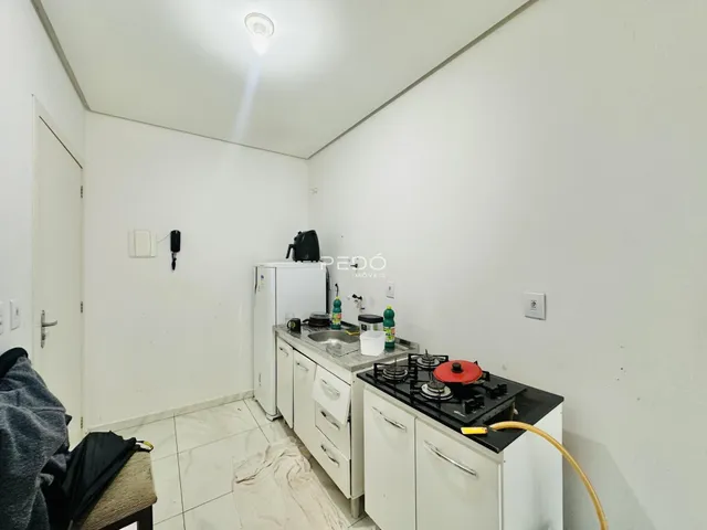Cozinha com armários brancos e piso de cerâmica em imóvel no Brasil.