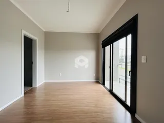 Sala de estar com piso de madeira e porta de vidro.