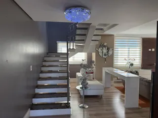 Foto de um interior mostrando uma escadaria e sala de estar com piso de madeira.