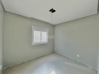 Ambiente interno de uma sala vazia com paredes cinzas e piso claro.