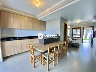Uma sala de jantar com mesa de madeira e armários de cozinha em um apartamento.