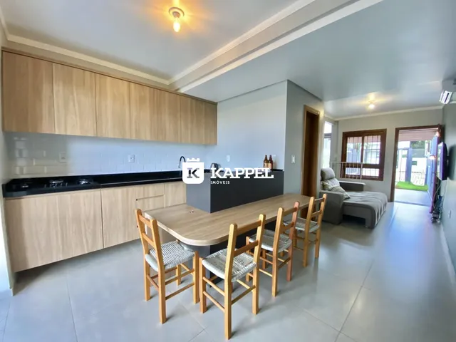 Uma sala de jantar com mesa de madeira e armários de cozinha em um apartamento.