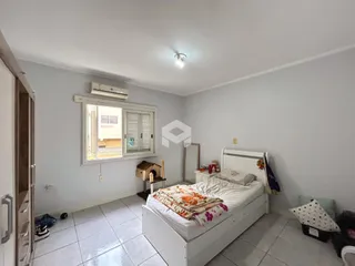 Quarto com cama e janela em ambiente claro.