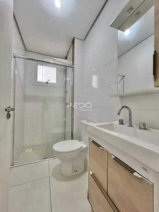 Banheiro com box de vidro e bancada de madeira.