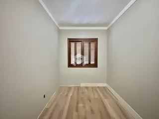 Hall de entrada com piso de madeira clara e parede branca.
