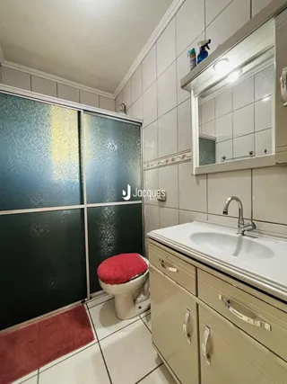 Foto de um banheiro com revestimento cerâmico e armário de bancada.