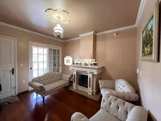 Sala de estar com piso de madeira, sofás e lareira em ambiente interno.