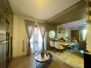 Sala de estar com piso de madeira e grandes janelas na residência.