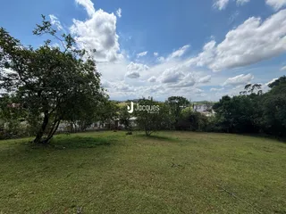 Vista de um gramado verde com árvores ao fundo.