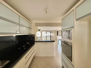 Cozinha moderna com armários brancos e bancadas escuras.