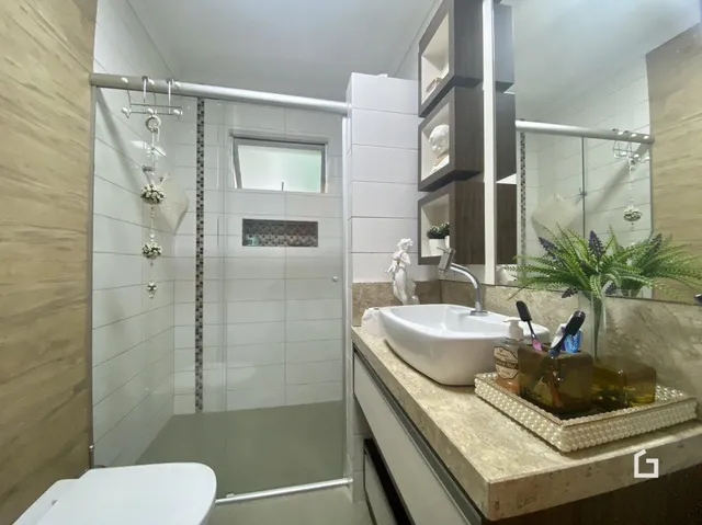 Banheiro moderno com revestimento branco e bancada de pedra.