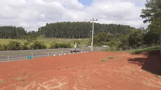 Paisagem de terra vermelha com vegetação e estrada no fundo.
