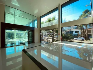 Sala de estar moderna com grandes janelas de vidro refletindo o ambiente.