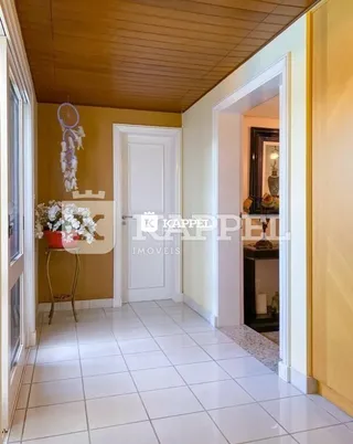 Hall de entrada com piso de cerâmica clara e teto de madeira.