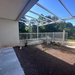 Vista externa com grade branca e estrutura de cobertura.