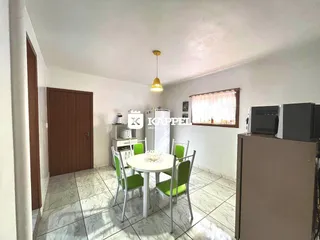 Sala de jantar com mesa redonda e cadeiras verdes em um ambiente claro.