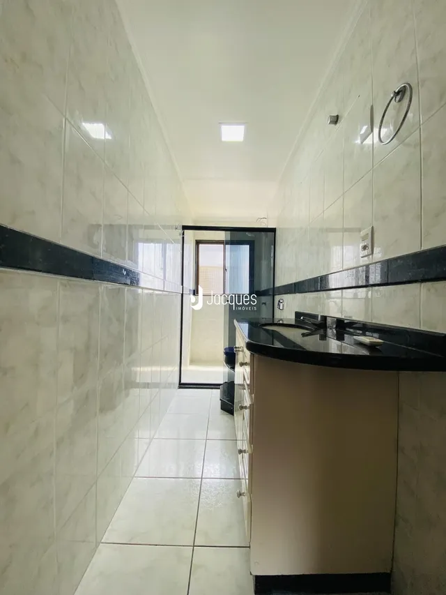 Corredor interno com revestimento cerâmico nas paredes e piso.