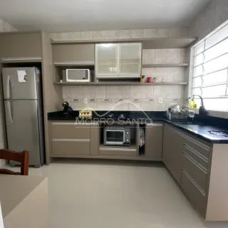 Cozinha com armários claros e bancada escura em um imóvel.