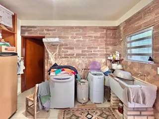 Interior de um ambiente com paredes de tijolo aparente e máquinas de lavar roupa.