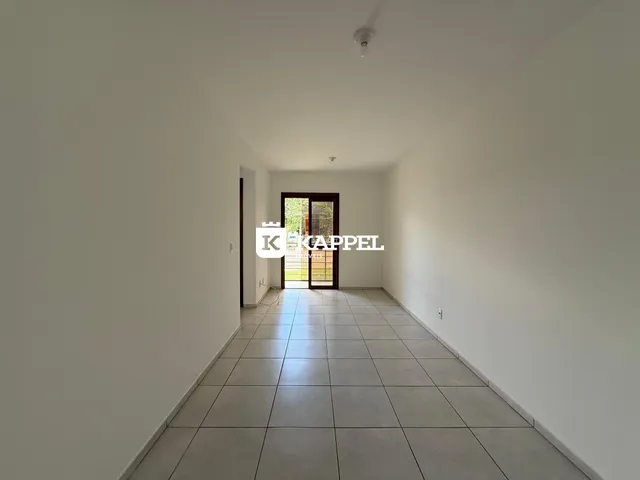 Foto de um corredor interno com piso de cerâmica claro e porta de vidro no final.