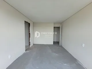 Hall da propriedade com paredes brancas e piso de concreto cru.