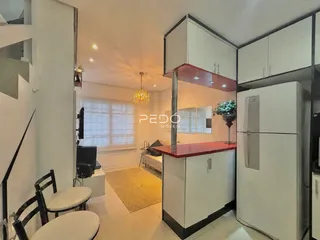 Vista da cozinha moderna com armários brancos e bancada vermelha em um imóvel no Brasil.