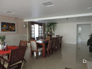 Sala de jantar com mesa de madeira e cadeiras em ambiente claro.