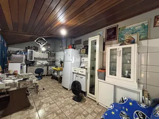 Interior de uma cozinha com armários brancos e piso de cerâmica.