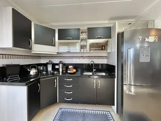 Cozinha moderna com armários escuros e bancadas pretas.
