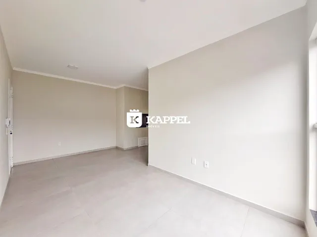 A sala de estar apresenta um piso de cerâmica clara e paredes brancas.