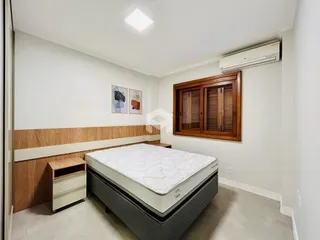 Quarto com cabeceira e armário de madeira em um imóvel no Brasil.
