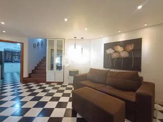 Sala de estar com piso xadrez preto e branco e sofá marrom.