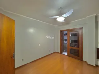 Interior de uma sala com piso de madeira e paredes brancas.