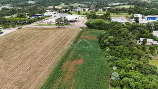 Vista aérea de uma propriedade mostrando um campo cultivado e vegetação circundante.