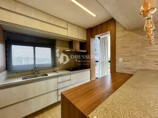 Vista da cozinha com armários brancos e bancada de granito.