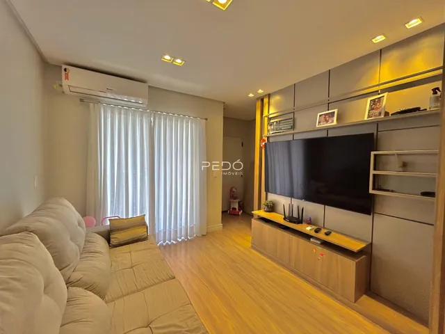 Sala de estar com sofá e parede de TV em um imóvel no Brasil.