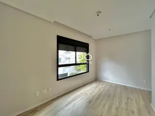 Sala com piso de madeira clara e grande janela.