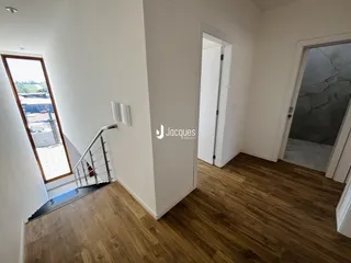Hall de entrada com piso de madeira e porta de acesso a outro cômodo.