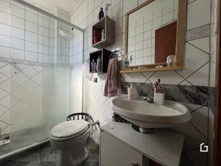 Foto interna de um banheiro com revestimento cerâmico branco.