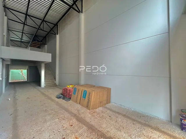 Vista interna de uma área em construção com paredes brancas e piso de cascalho.