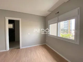 Interior de uma sala com piso de madeira e janela.