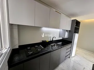 Uma cozinha moderna com armários brancos e bancadas escuras.