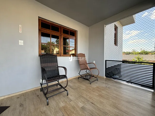 Uma sala de estar com piso de madeira e janelas de madeira.