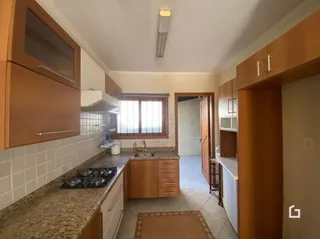 A cozinha apresenta armários de madeira e revestimento cerâmico.