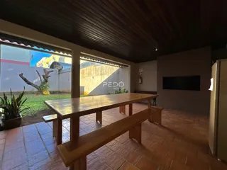 Sala de jantar com grande mesa de madeira e vista para o jardim externo.