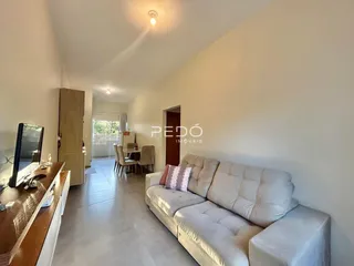 Sala de estar com sofá claro e piso de porcelanato em um imóvel no Brasil.