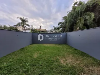 Vista externa de um terreno com gramado e muro de vedação.