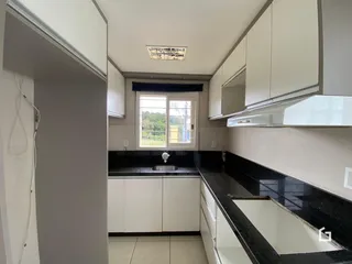 Foto de uma cozinha com armários brancos e bancadas escuras.
