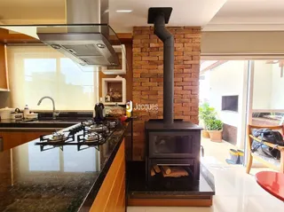 Cozinha com bancada escura e parede de tijolos aparentes.